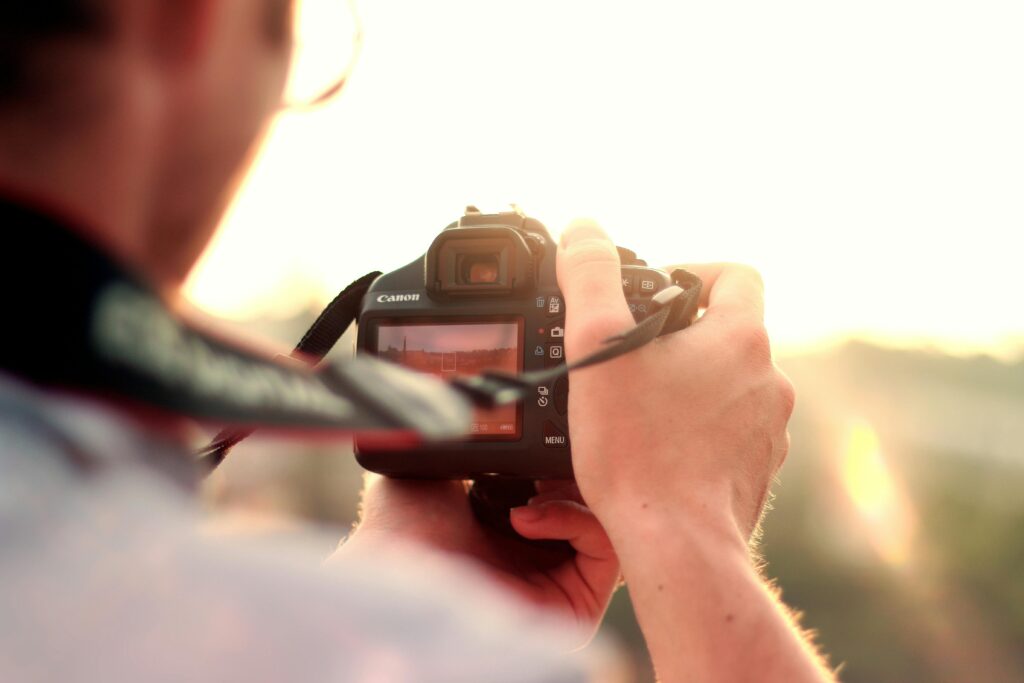 Photographer holding a DSLR camera while shooting outdoors at sunset