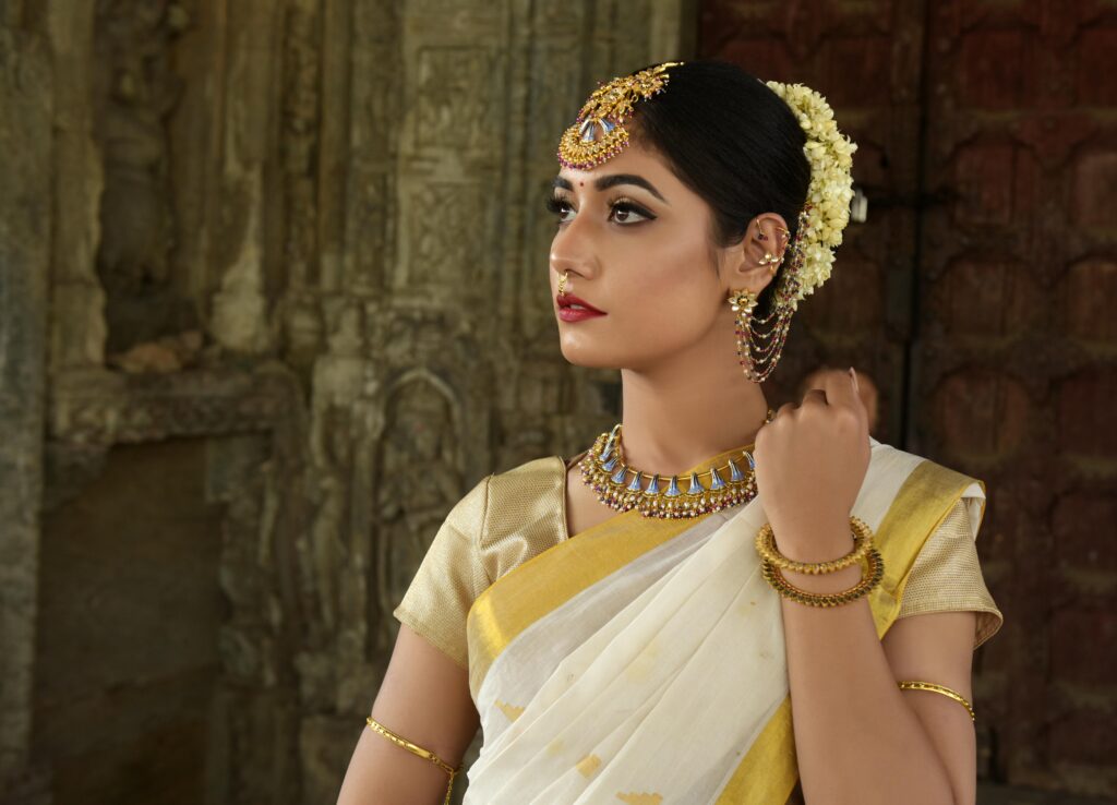 pexels-photo-1162983-1162983 Beautiful Indian woman in traditional saree, adorned with exquisite jewelry, set against historic architecture.